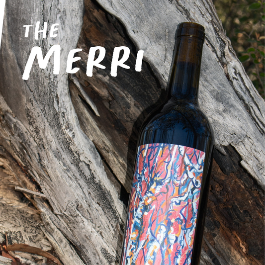 Wine bottle with colorful label on a wooden background, featuring the brand 'The Merri'.